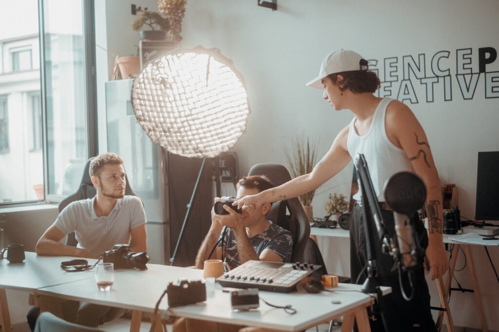 Formation en photographie dans un studio créatif, trois personnes discutent de l'utilisation d'un appareil photo.