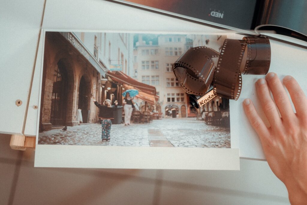 Photo argentique d'un enfant jouant dans une rue pavée, avec une pellicule Kodak en premier plan.